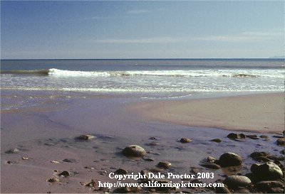 Scenic beach picture of flowing water, blue sky, rocks on sand coast photos