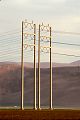 picture of towers in evening light California agricultural land lines over field, hill tall steel structures, summer